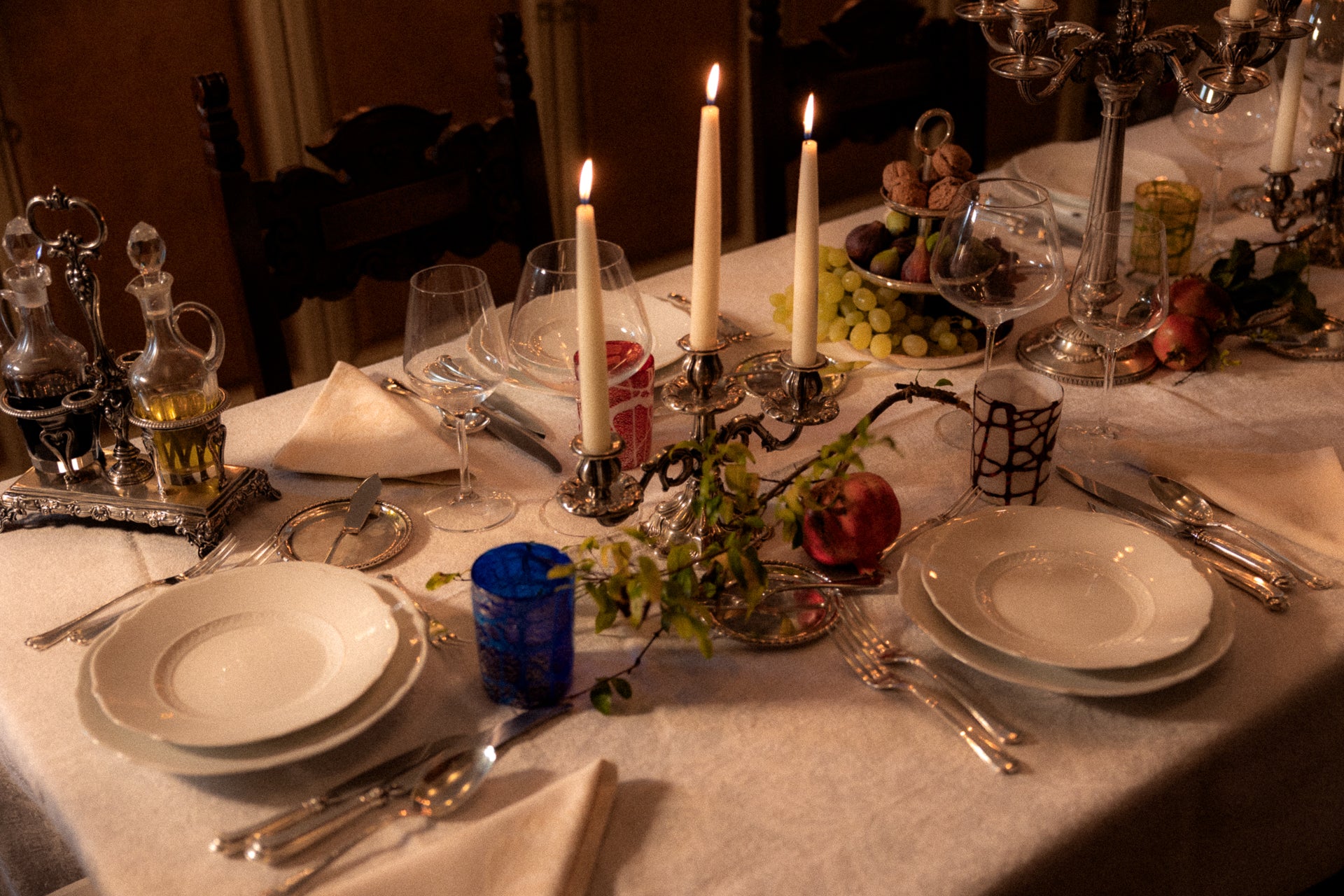 Elegant Dining table set for a meal with plates, candles, hand-made glasses as tumblers made in Venice