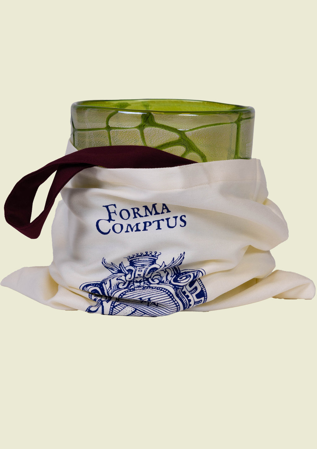 Beige, clear tote bag with 'Forma Comptus' branding holding a hand-blown green vase made in venice