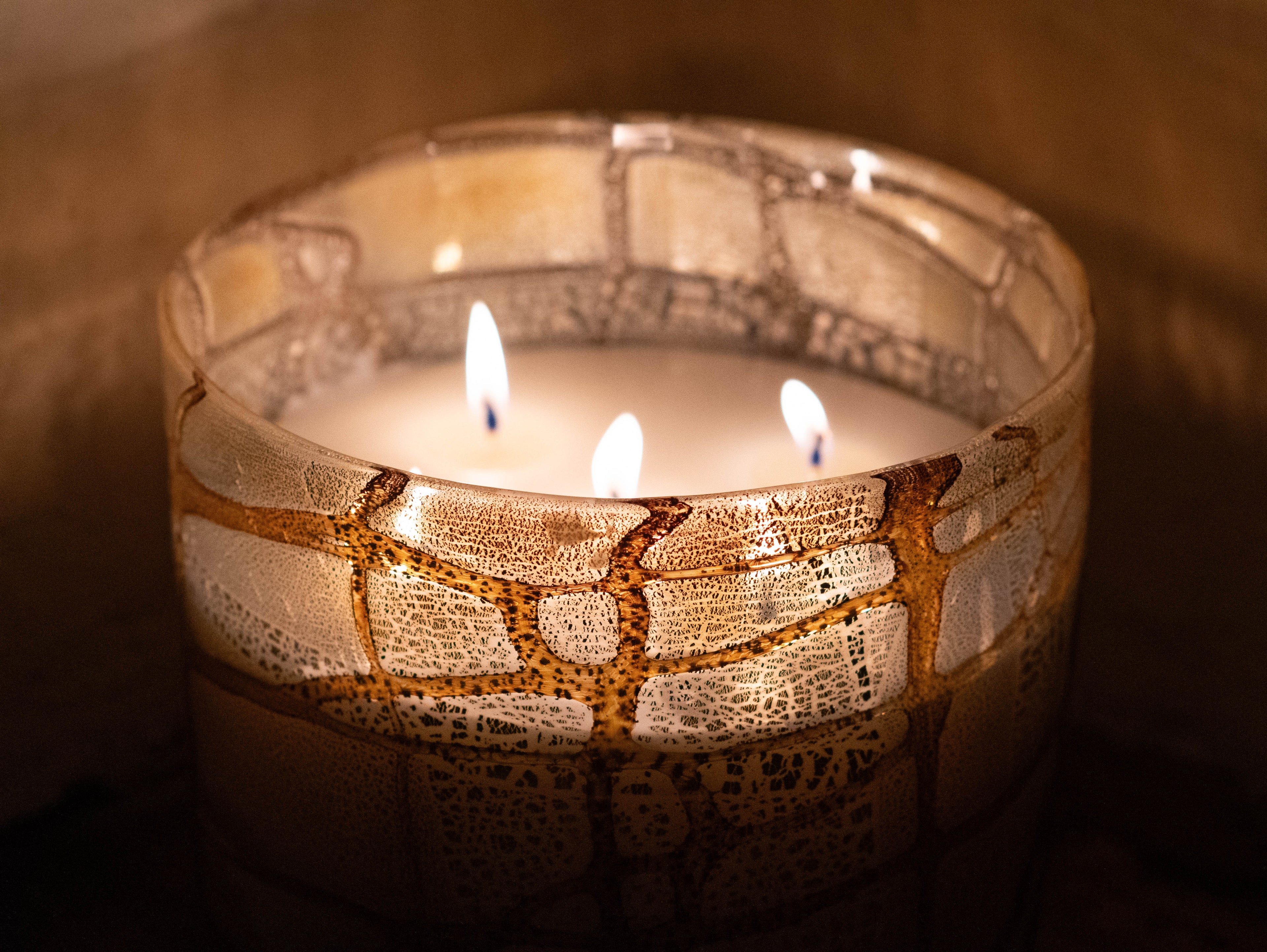 Close-up of hand-blown vase candle, with golden enamel layered over pure silver leaf
